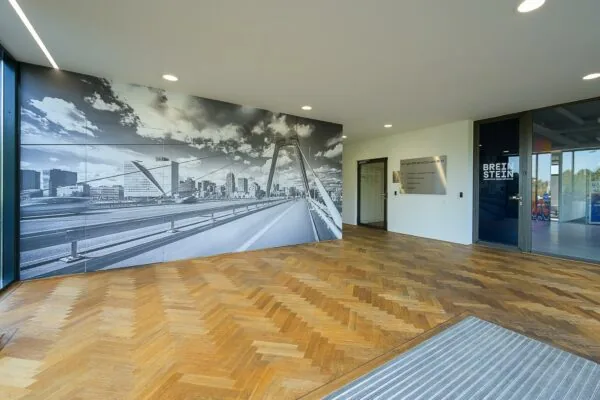 In de entree van een modern kantoorpand aan de K.P. van der Mandelelaan hangt een grote zwart-wit muurfoto van de Erasmusbrug in Rotterdam.